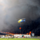 A helicopter prepares to throws water over the fire.